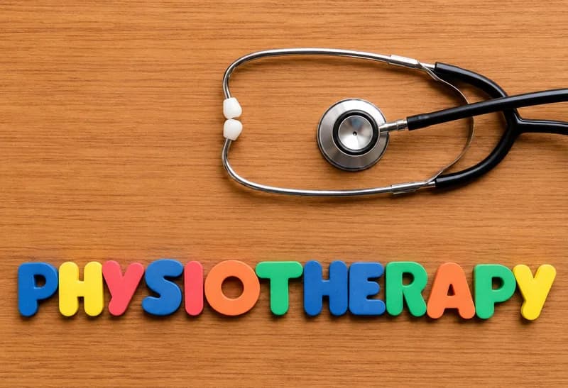 The word physiotherapy spelled in colourful letters beside a stethoscope on a wooden desk